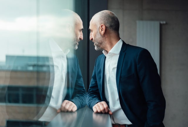 Business man looks through window at the city below